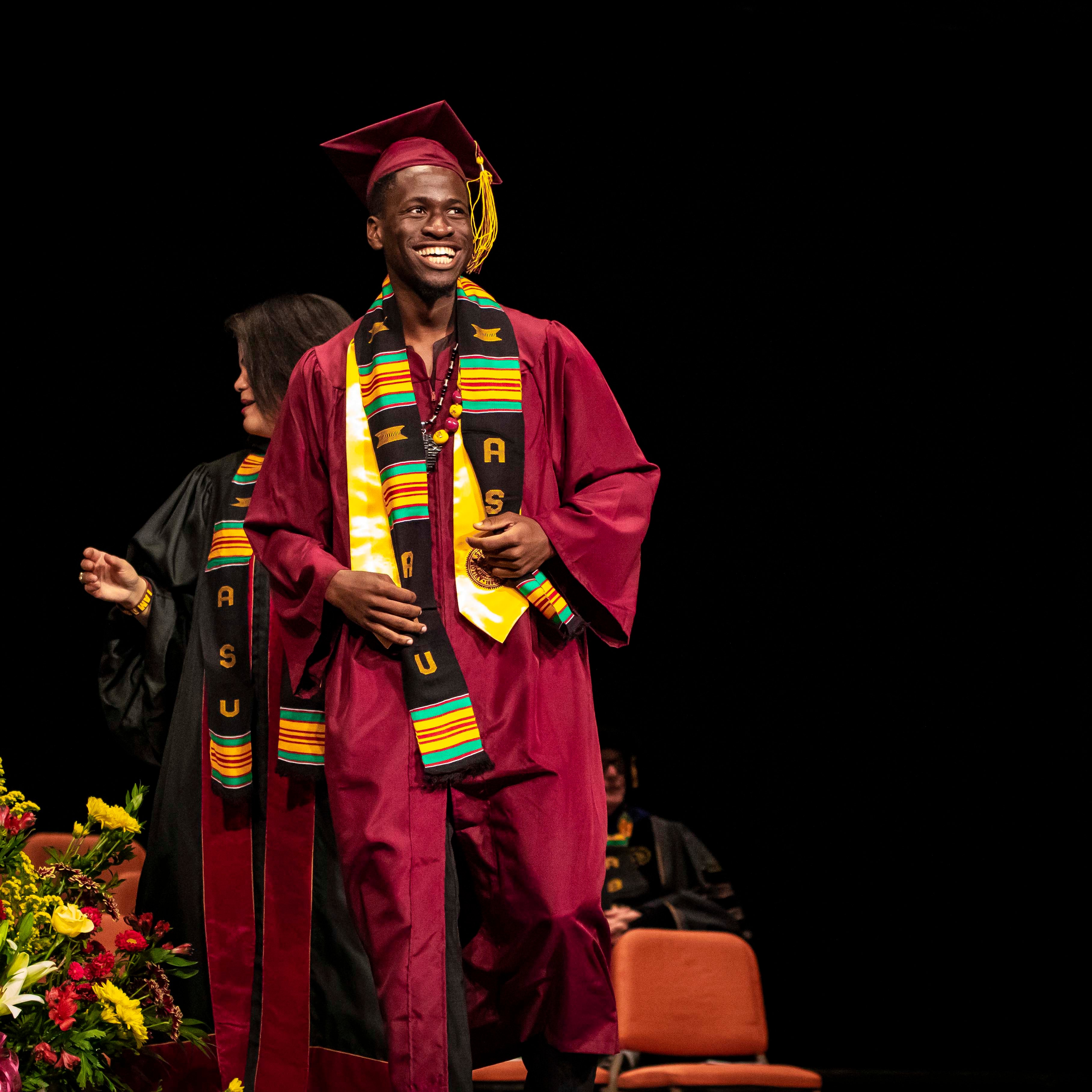 ASU Black African Convocation male graduate onstage with his stole and cap and gown