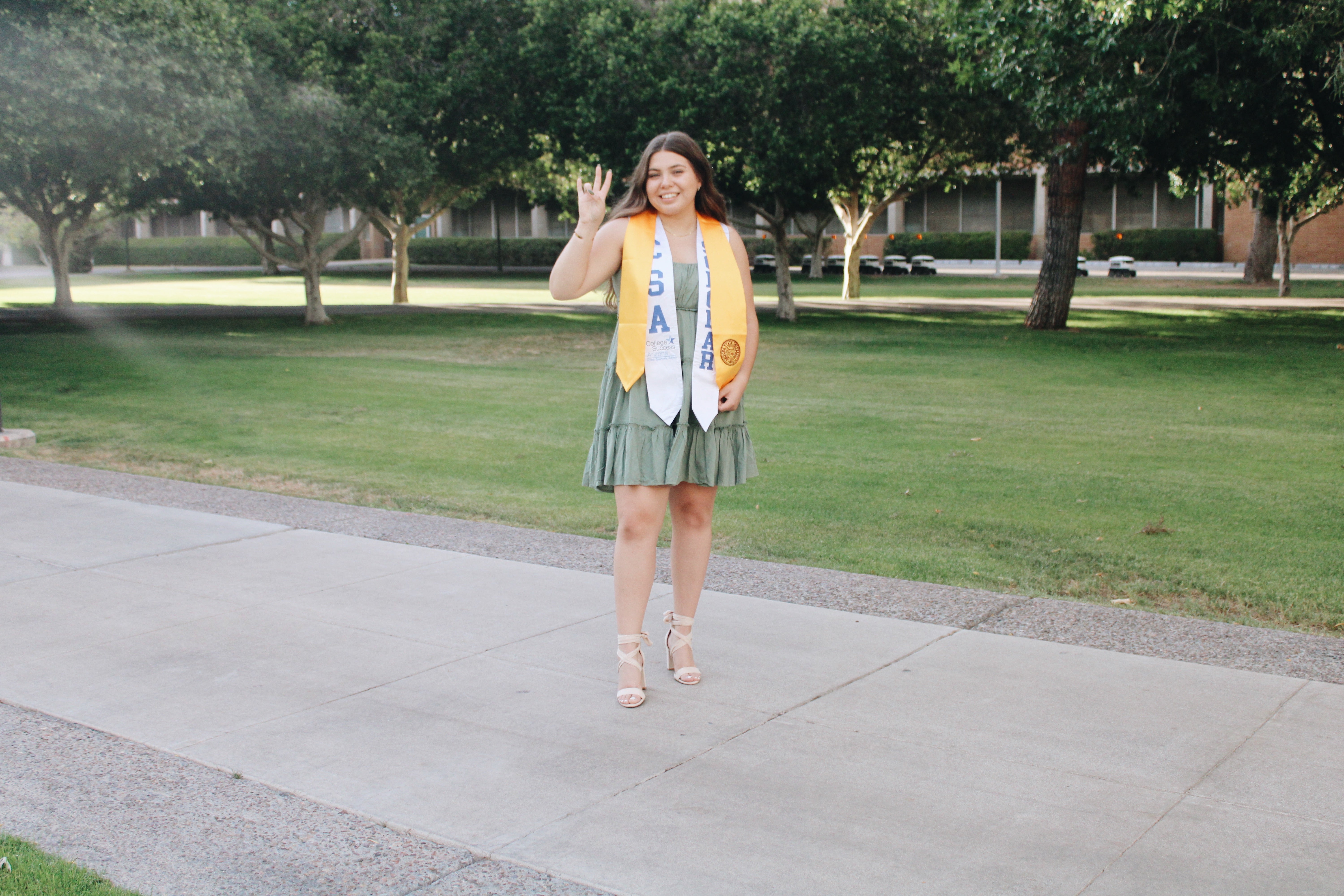 ASU Grad Carmen De Alba Cardenas holds up the pitchfork hand signal for a graduation photo.