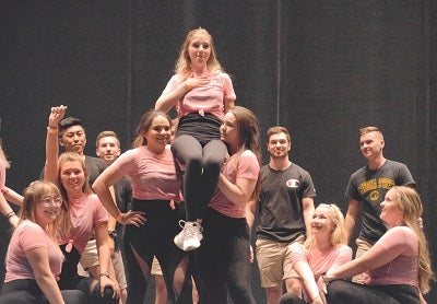 Students in black and pink clothing perform a musical number