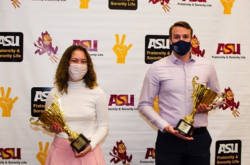 Two masked ASU students with Greek Week trophies