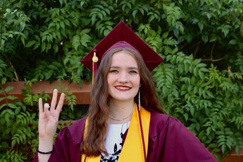  in her cap and gown giving a forks up sign